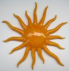 an orange sun shaped object on a white surface