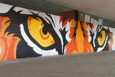 a large mural painted on the side of a building with orange and black flames coming out of it