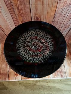 a black and white plate sitting on top of a wooden table next to a wall