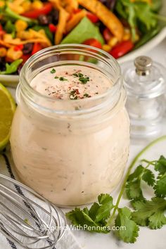 a salad with dressing in a jar next to it