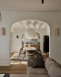 a living room filled with furniture next to a dining room table and chairs on top of a hard wood floor