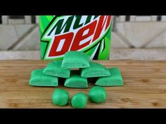 a can of mountain dew next to some green gummy bears on a wooden table