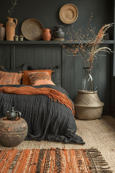 a bed with an orange and black bedspread in a room filled with vases