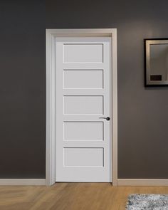 an empty room with a white door and rugs on the wooden floor next to it