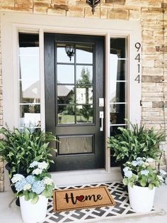 two potted plants are sitting on the front porch with a door mat that says hello