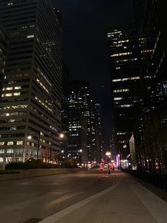 a city street at night with skyscrapers lit up