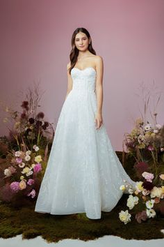 a woman standing in front of flowers wearing a white dress