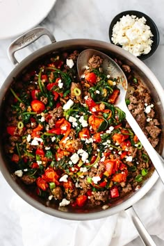 a pot filled with meat, vegetables and feta cheese