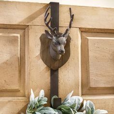 a deer head mounted to the side of a wooden door with green leaves on it