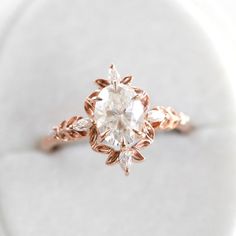 a close up view of a diamond ring on a white surface with the center stone in rose gold