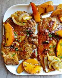 a white plate topped with meat and veggies next to potato wedges on top of a table