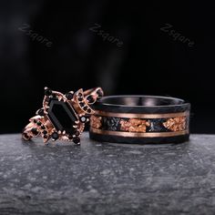 two rings with black and gold designs on them sitting on top of a stone surface