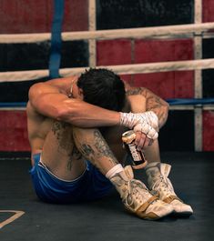 a man with tattoos sitting on the ground