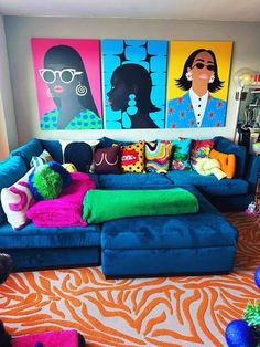 a living room filled with blue couches and colorful paintings on the wall behind them