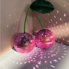 two pink disco ball vases sitting on top of a white table next to a green leaf