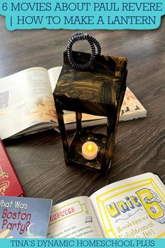 an open book sitting on top of a wooden table next to two books and a candle