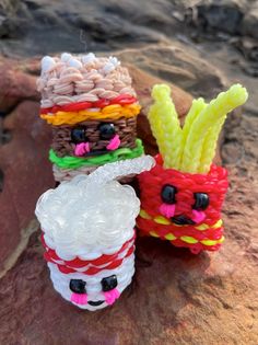 three plastic cups with food on them sitting next to each other in front of some rocks