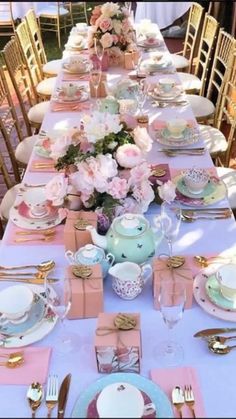 a table set up for a tea party with pink and white plates, silverware, napkins, cups and saucers