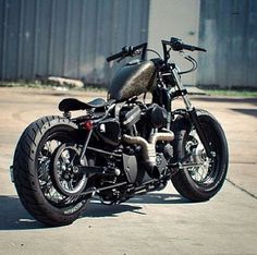 a black motorcycle parked on top of a cement road next to a metal building with a blue door