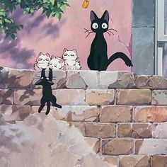 three black cats sitting on top of a brick wall next to a tree and window