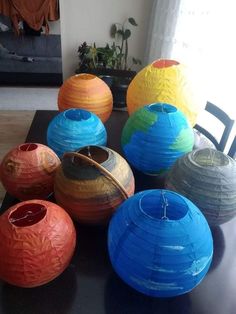 several colorful vases sitting on top of a black table next to a planter