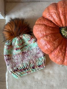 two knitted pumpkins sitting next to each other on the floor, one with a brown pom - pom