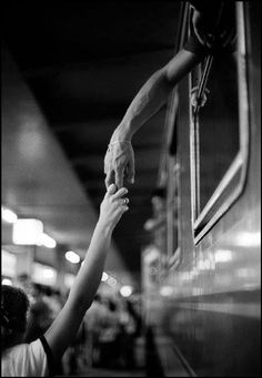 two people reaching for something on the side of a subway car with their hands in the air