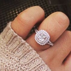 a woman's hand with a diamond ring on top of her finger, wearing a sweater