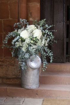 a metal bucket filled with white flowers sitting on top of a set of steps