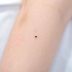 a small heart tattoo on the back of a woman's arm