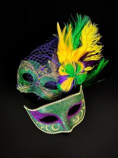 two masquerade masks with feathers on black background