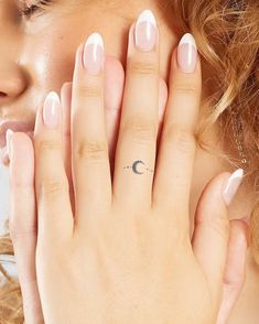 a woman's hand with a small crescent tattoo on her left thumb, and a half moon tattooed on the middle finger