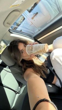 a woman sitting in the back seat of a car drinking water