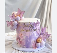 there is a purple cake with pink butterflies on the top and gold decorations around it