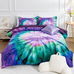 a bed covered in purple and green tie - dyed comforters with pillows on it