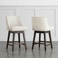 two white upholstered barstools with wooden legs