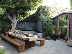 a wooden bench sitting in the middle of a garden next to a table with plates on it