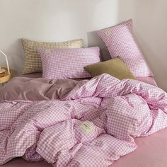 an unmade bed with pink and white checkered comforter, pillows and pillowcases