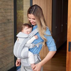 a woman holding a baby in a carrier