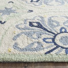 an area rug with blue and green flowers on the bottom, in front of a wooden floor