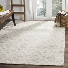 a white area rug with a wooden bench in front of it and a window behind it