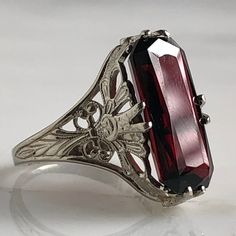 Details: Stunning Edwardian Period garnet and 14K white gold filigree ring! The stone measures 14.5mm by 7mm, and the is 4.6mm above the finger at the highest point on the ring. The filigree is beautiful on this ring, and is in lovely shape. This is a stunning ring--you will not be disappointed! Please ask all necessary questions prior to placing an order. Measurements: The size is 4 1/2 US and can be sized for a fee. Condition: The overall all condition of this ring is very good. Victorian Engraved Filigree Ring For Formal Occasions, Art Deco Engraved Filigree Ring For Formal Occasions, Antique Filigree Engraved Ring For Formal Occasions, Antique Engraved Filigree Ring For Formal Occasions, Elegant Oval Ruby Ring With Intaglio, Formal Silver Ruby Ring In 14k White Gold, Elegant Formal Engraved Hallmarked Ring, Victorian Filigree Ring With Diamond Cut For Formal Occasions, Vintage Ruby Ring With Filigree For Wedding