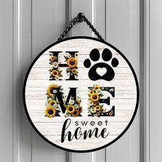 a sign that says home sweet home with sunflowers and dog's paw