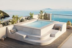 an outdoor hot tub on a deck overlooking the ocean with cactus trees in the foreground