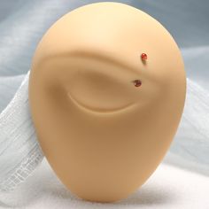 a dummy with two tiny red stones on it's nose and behind it is a white cloth