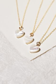 This Mother of Pearl Heart Necklace is a perfect way to bring the perfect pop of white to any look. Created with a delicate heart pendant crafted from mother of pearl shell, it is ideal for layering and brings a touch of daintiness to any style. Its neutral hue makes it a go-to piece for all your looks. This is also part of our Mama + Me collection so you can match with your Little. Size: 10 mm Mother of Pearl shell heart Each shell heart is natural and unique Shell heart is wire-wrapped to fine Elegant Mother Of Pearl Shell Necklace Gift, Pearl Heart Necklace, Elegant Mother Of Pearl Shell Necklace, Mother Of Pearl Heart Necklace, Mother's Day Heart-shaped Pearl Pendant Necklace, Shell-shaped Mother Of Pearl Necklace With Pearl Pendant, Everyday Wear Jewelry, Mother Of Pearl Jewelry, Gold Heart Necklace