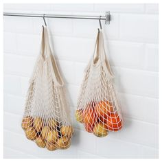 two bags filled with fruit hanging from hooks