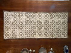 an old rug is on display with other antique dishes and spoons in front of it