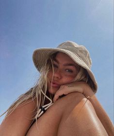 a woman wearing a hat sitting on the beach