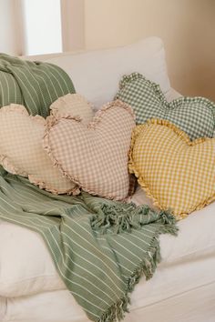 three heart shaped pillows on a white couch